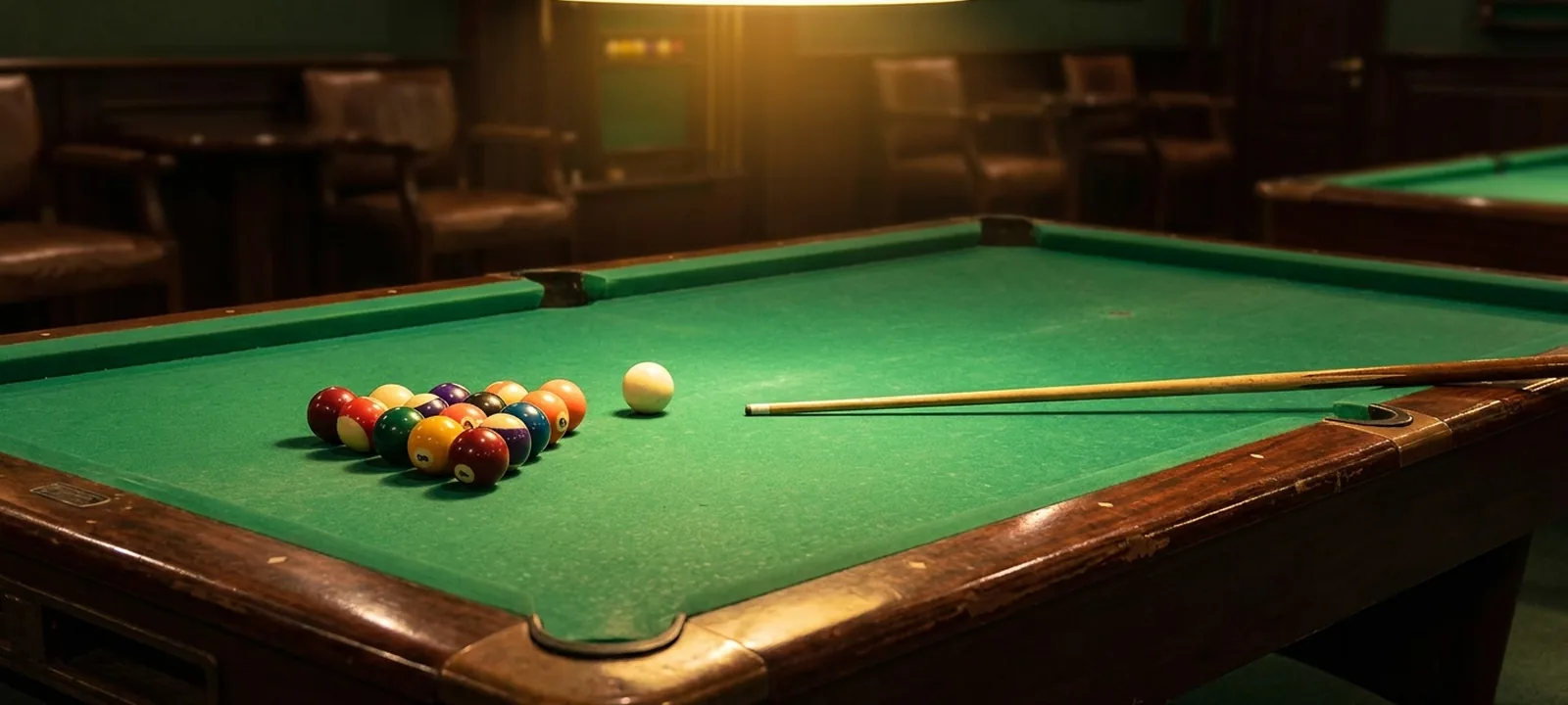 Billardtisch mit grünem Tuch, angeordneten Kugeln und Queue in einem Billardsalon