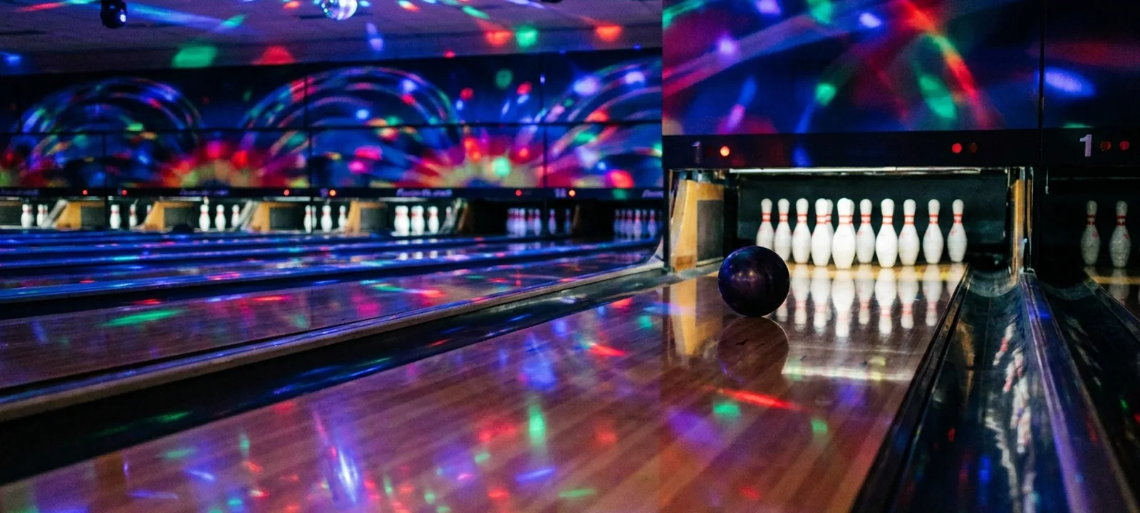 Moderne Bowlingbahn mit rollender Kugel und weißen Pins am Ende