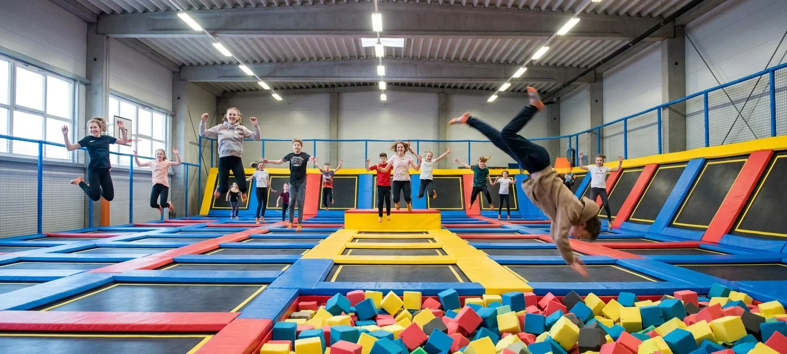 Jugendliche springen in einer großen bunten Trampolinhalle in die Höhe